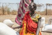 Adeng, 18, who is pregnant, waits with her food aid at distribution point