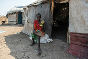 Adeng, 18, who is pregnant, sits outside her makeshift home after being displaced by conflict